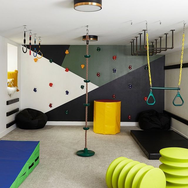 an indoor gym area with climbing ropes and exercise mats on the floor, in front of a colorful wall