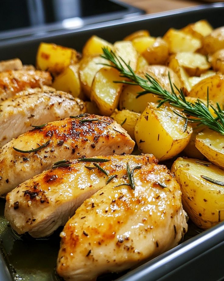 chicken, potatoes and rosemary garnish in a pan