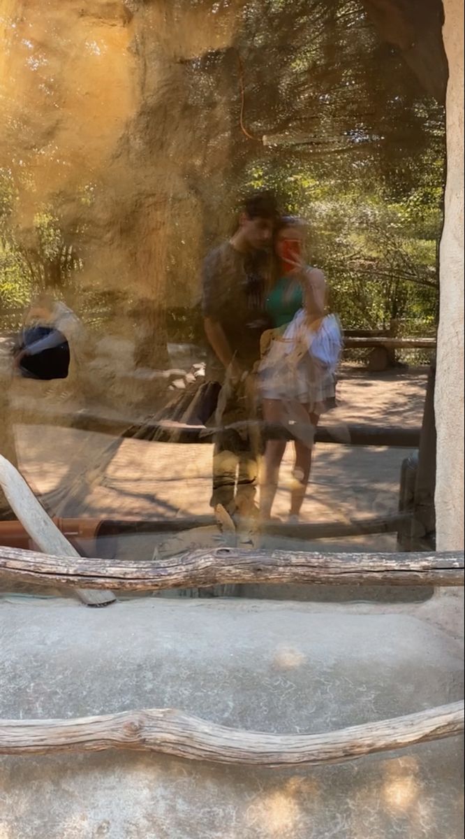 a man and woman are standing in front of a glass window with the reflection of a giraffe