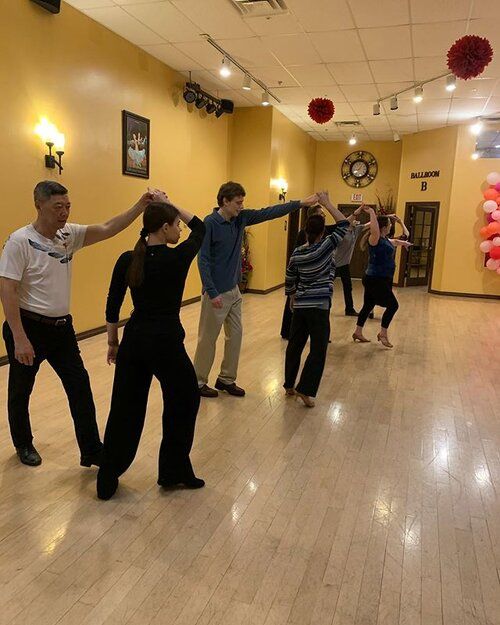 a group of people standing on top of a hard wood floor in a dance studio