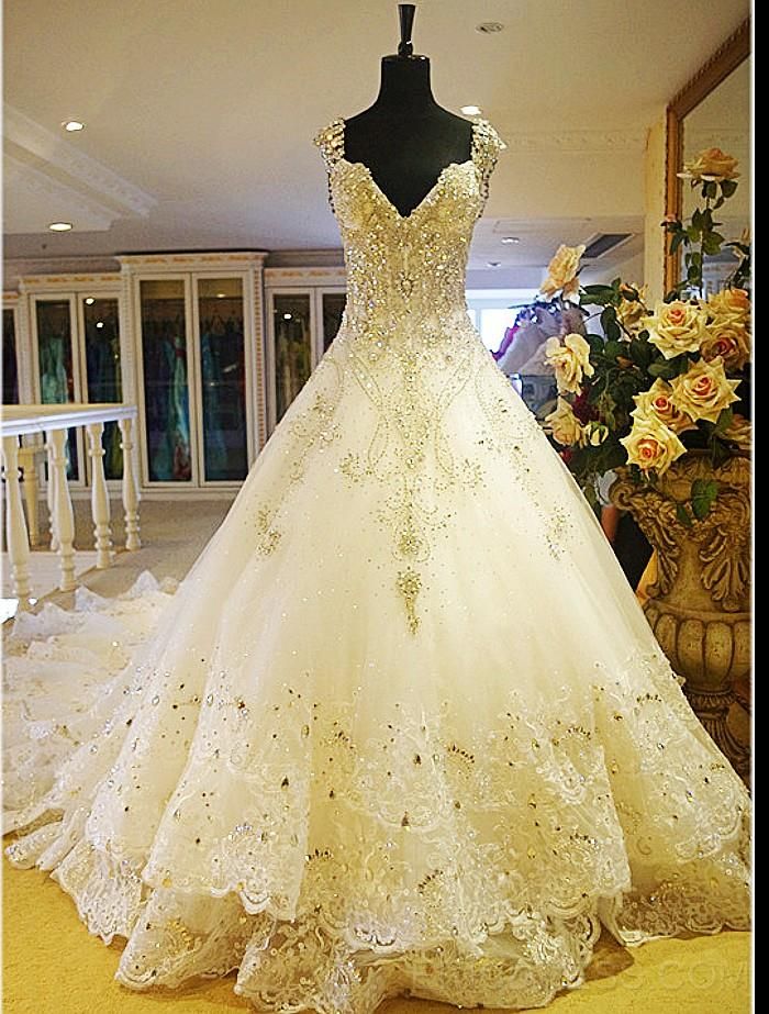 a wedding dress on display in front of a flower vase with roses and flowers behind it