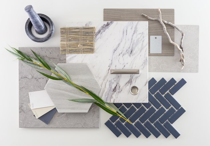 marble tiles and accessories are arranged on a white surface with a green plant in the middle