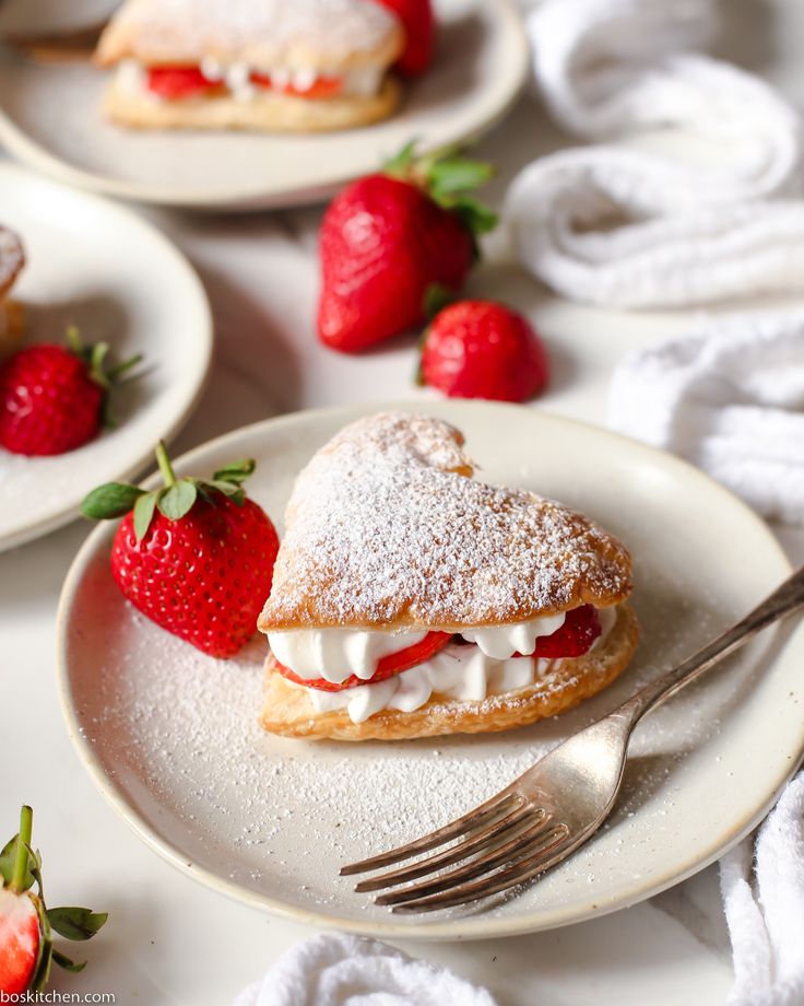 strawberry shortcakes with powdered sugar and fresh strawberries on white plates, ready to be eaten