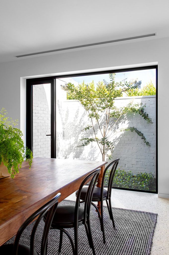 a dining room table with chairs and a potted plant next to the sliding glass door