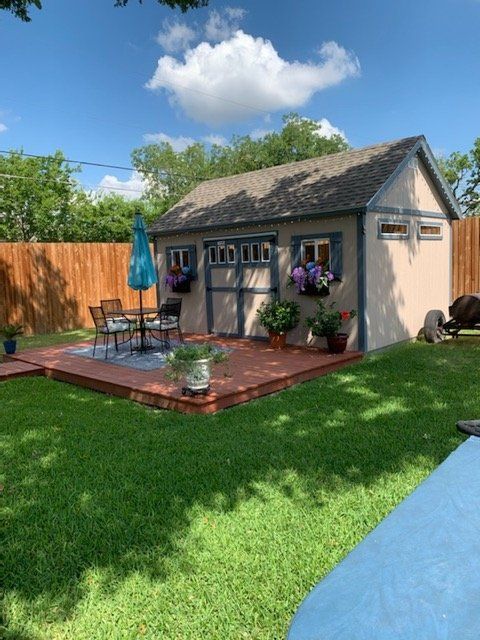 a backyard with a shed, deck and patio furniture in the back yard on a sunny day