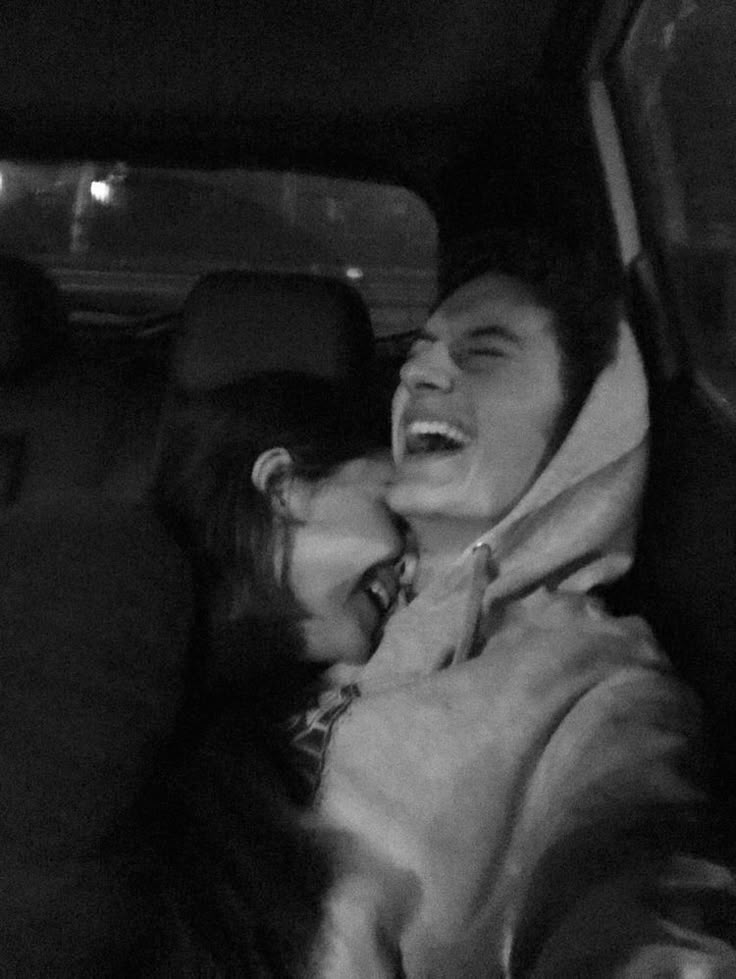 black and white photograph of two people in the back seat of a car, laughing