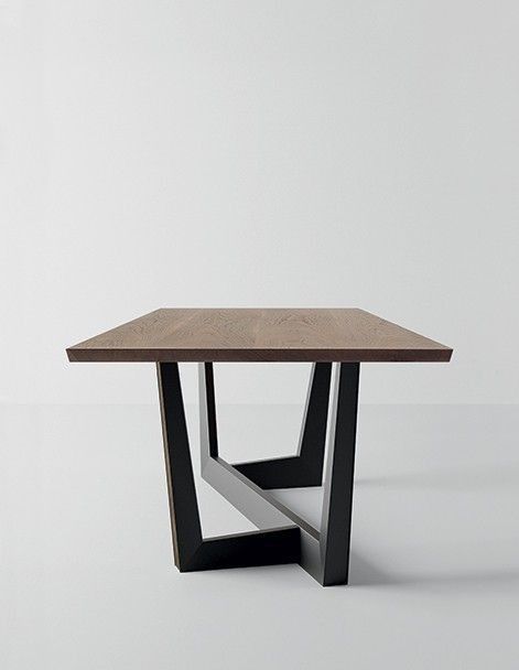 a square wooden table with black metal legs and a white wall in the back ground