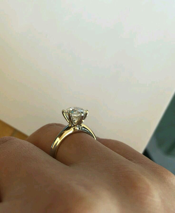 a person's hand holding a diamond ring