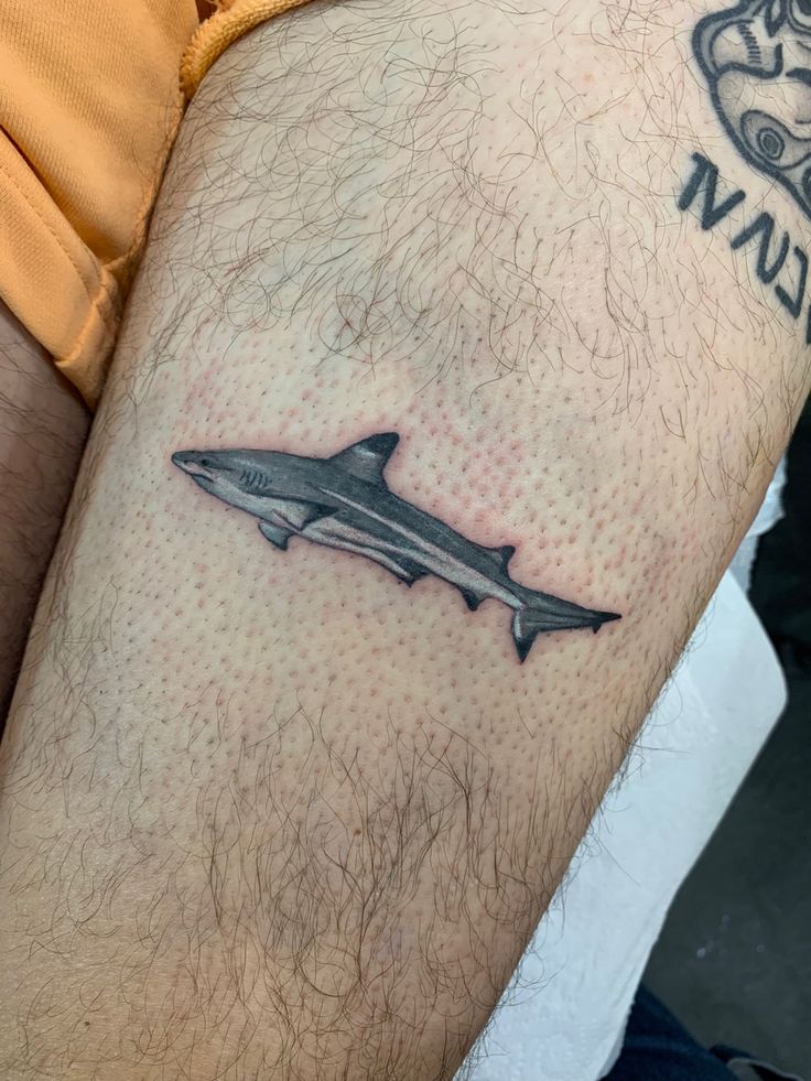 a man's arm with a tattoo on it that has a shark on it