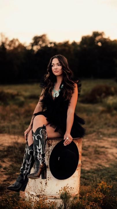 a beautiful woman sitting on top of a wooden stump