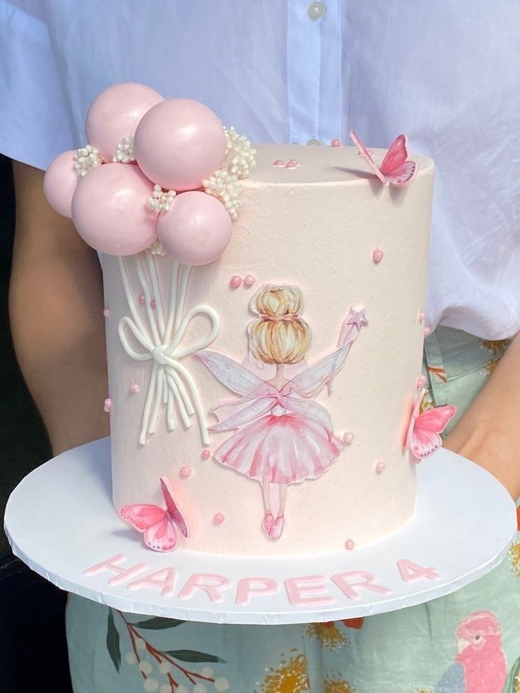 there is a cake that has pink balloons on it and a ballerina figure on top