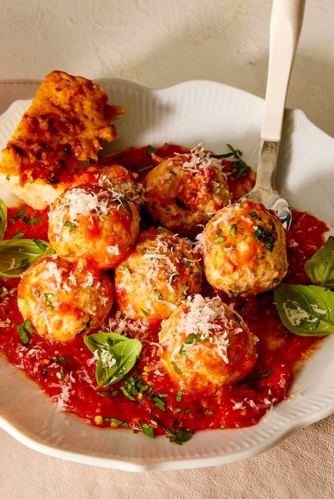 a white plate topped with meatballs covered in marinara sauce and parmesan cheese