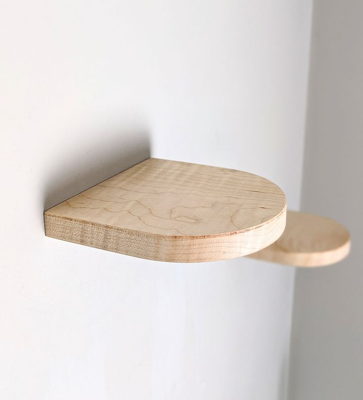 a wooden shelf mounted to the side of a wall next to a white painted wall