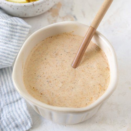 a bowl filled with food next to a wooden spoon