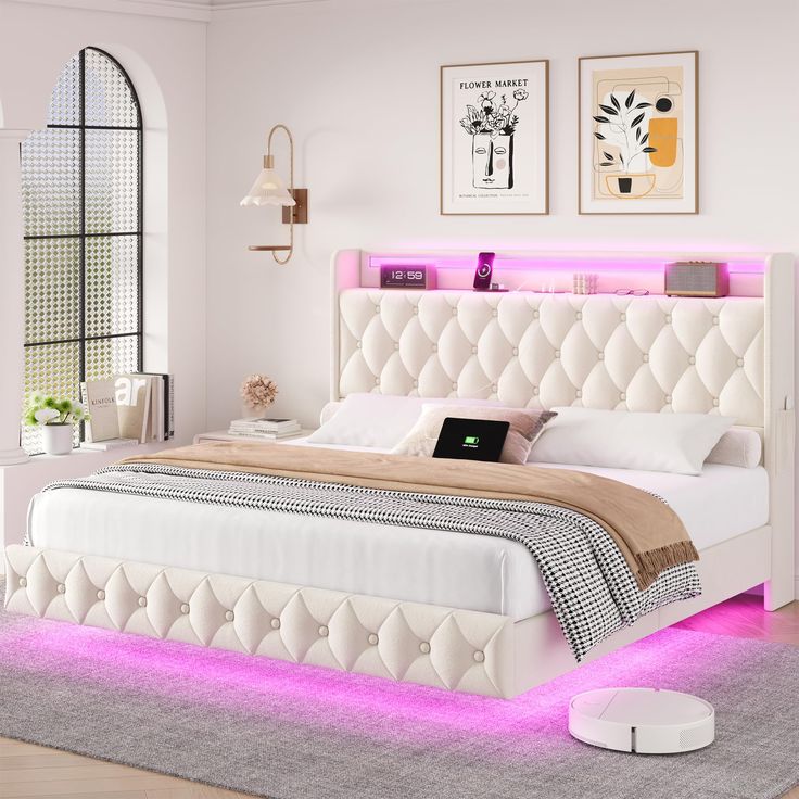 a white bed with pink lights on the headboard and foot board in a bedroom