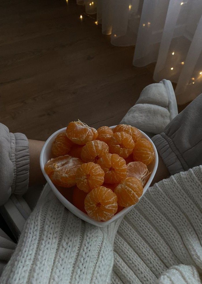 a person holding a white bowl filled with peeled oranges