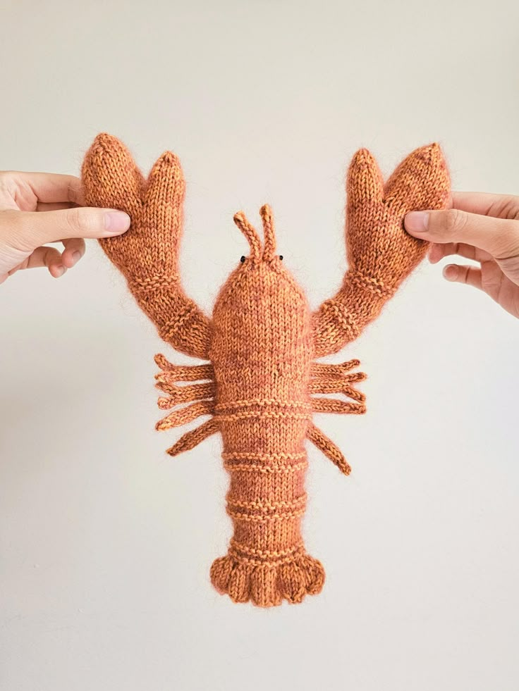 two hands holding up a knitted lobster