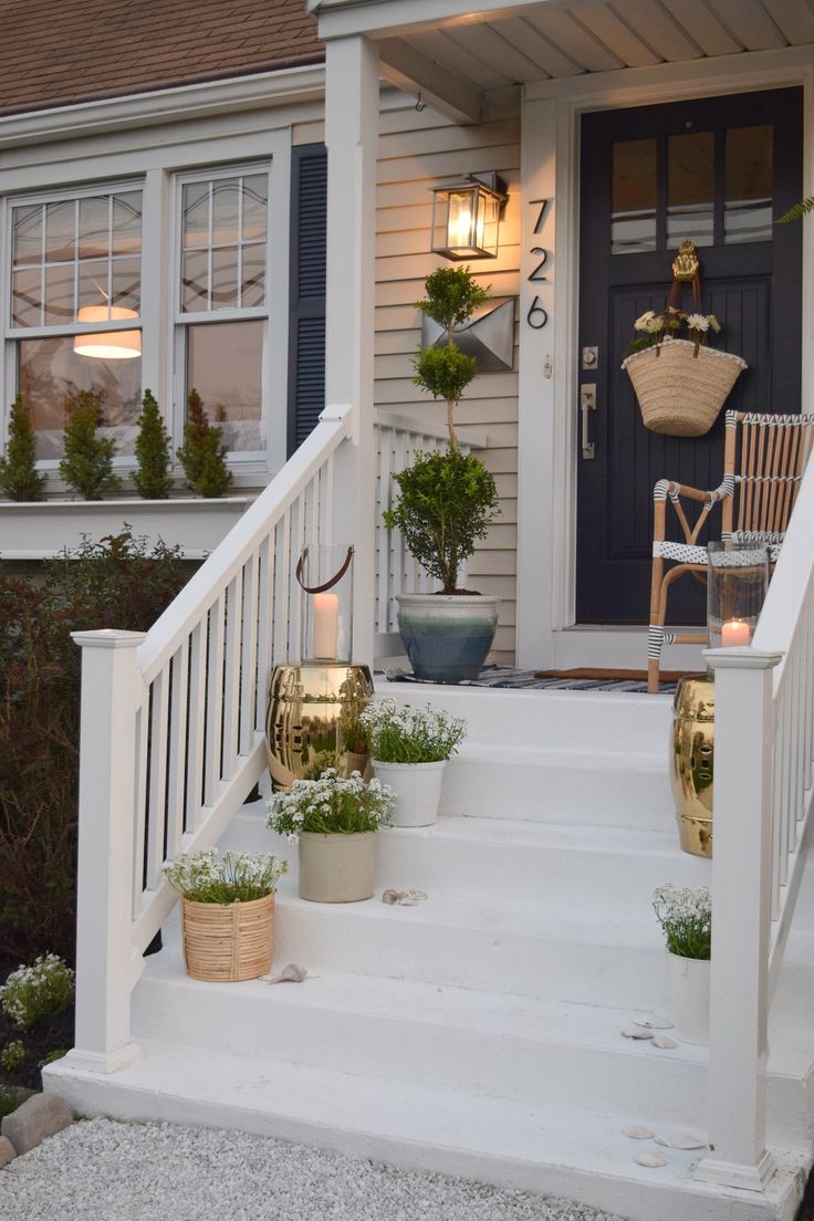 the front porch is decorated with potted plants and lights on it's steps