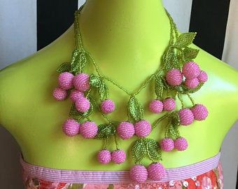 a green mannequin with pink flowers on it's chest and two necklaces hanging from the neck