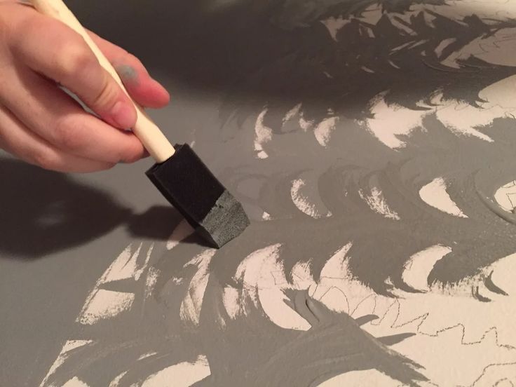 someone using a brush to paint a wall with black and white designs on the walls