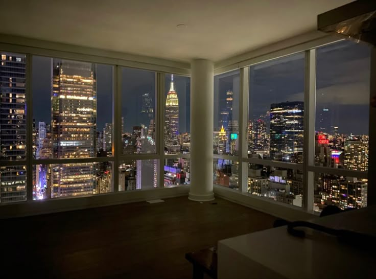 an empty room with large windows overlooking the city lights at night in new york's financial district