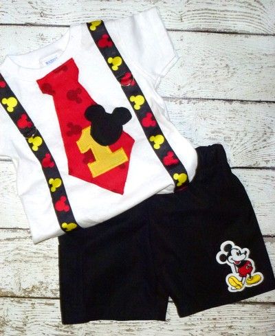 a shirt and shorts with mickey mouse on it are sitting on a white wooden surface