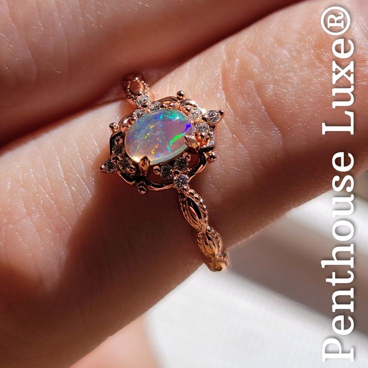 a woman's hand holding an opal ring