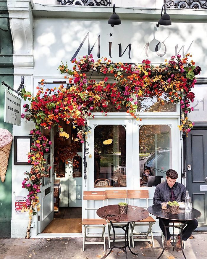 a man sitting at a table in front of an ice cream shop with flowers on it