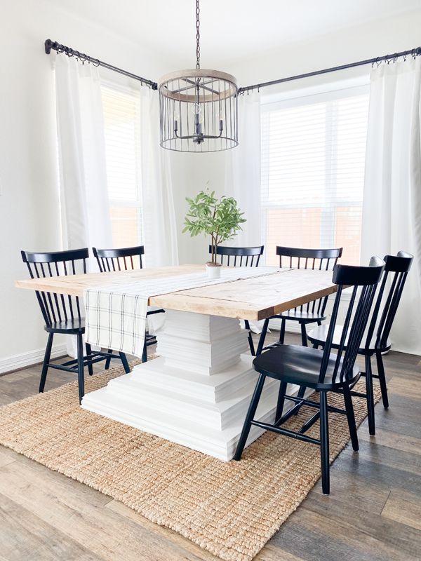 a dining room table with four chairs and a rug on the floor in front of it