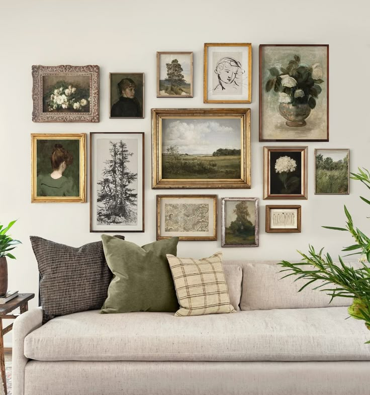 a living room filled with lots of framed pictures on the wall above a white couch