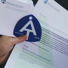 a person holding up a blue and white sticker with the letter a on it