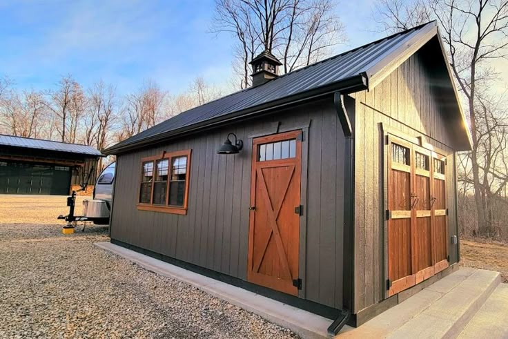 a small gray building with wooden doors and windows