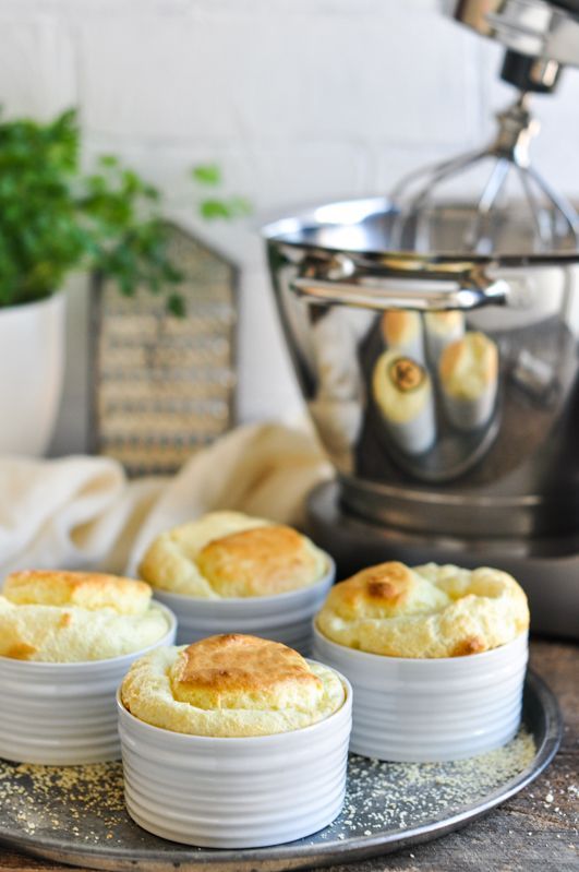 four small white bowls filled with food sitting on top of a metal tray next to an electric mixer