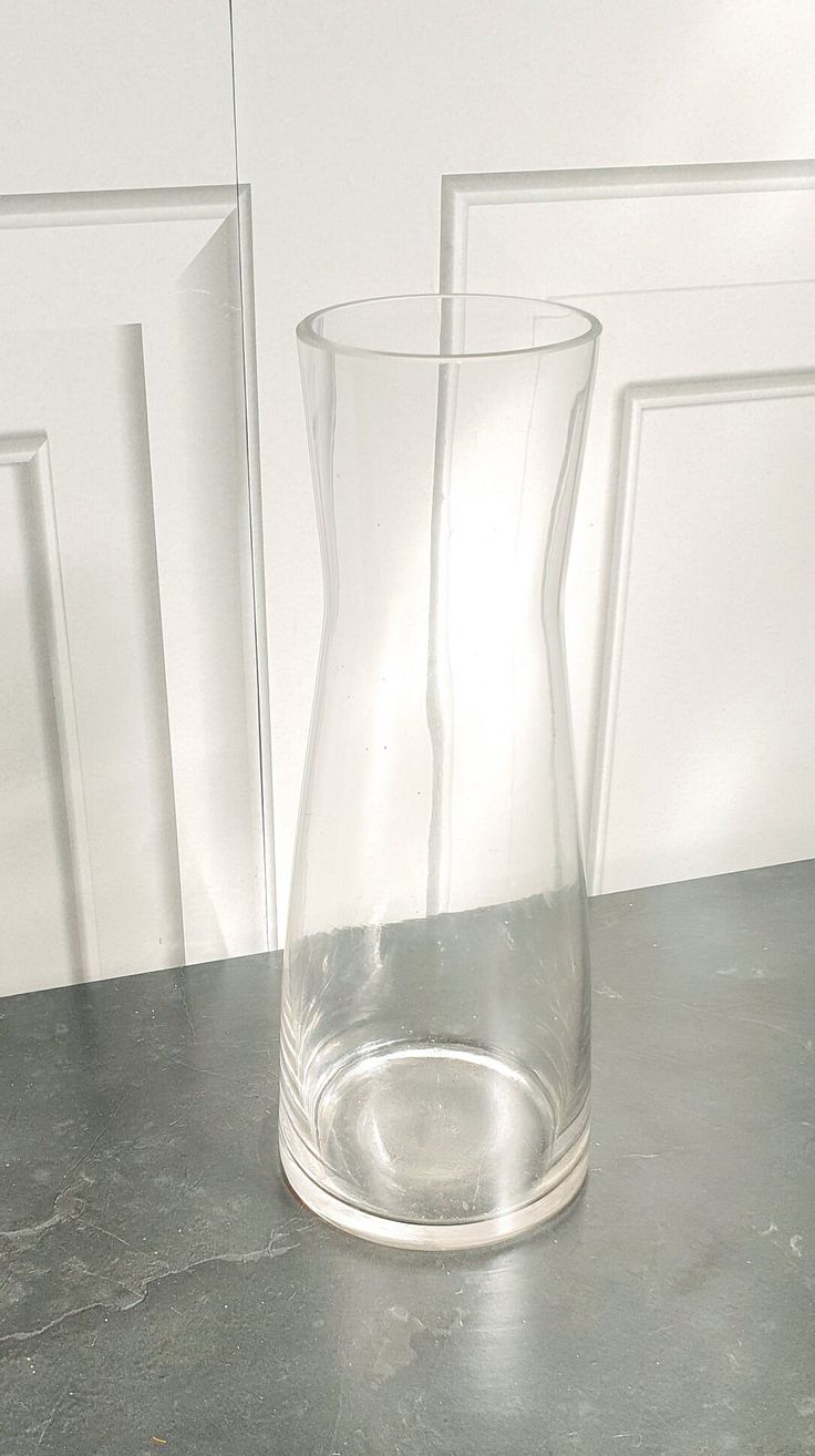 a clear vase sitting on top of a counter next to a white wall and door