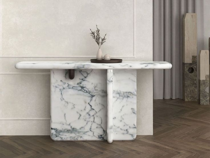 a white marble table with a plant on top in front of a wall and wood flooring