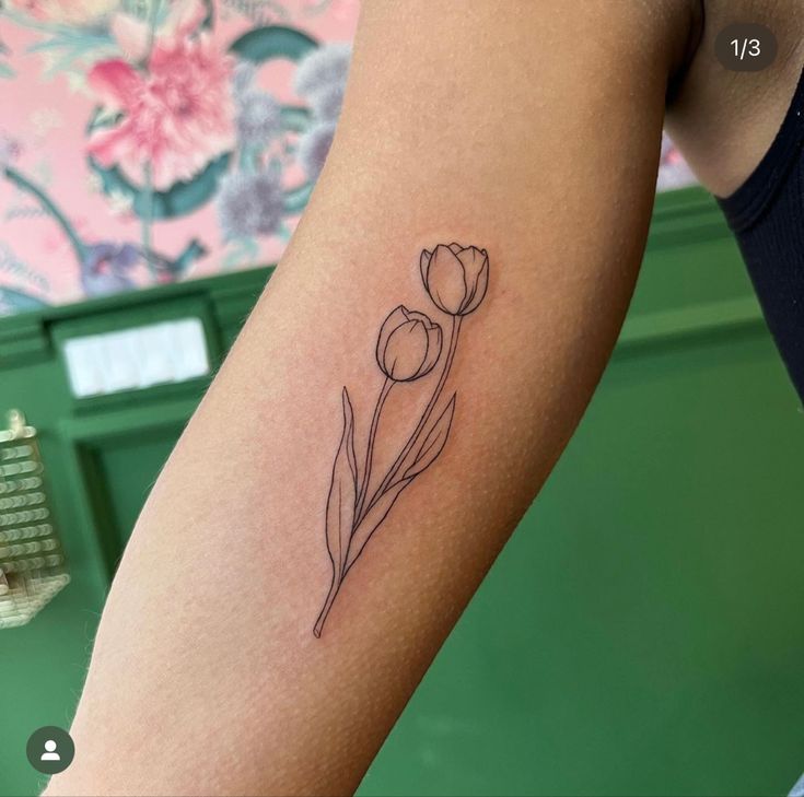 a woman's arm with a single flower tattoo on the back of her left arm