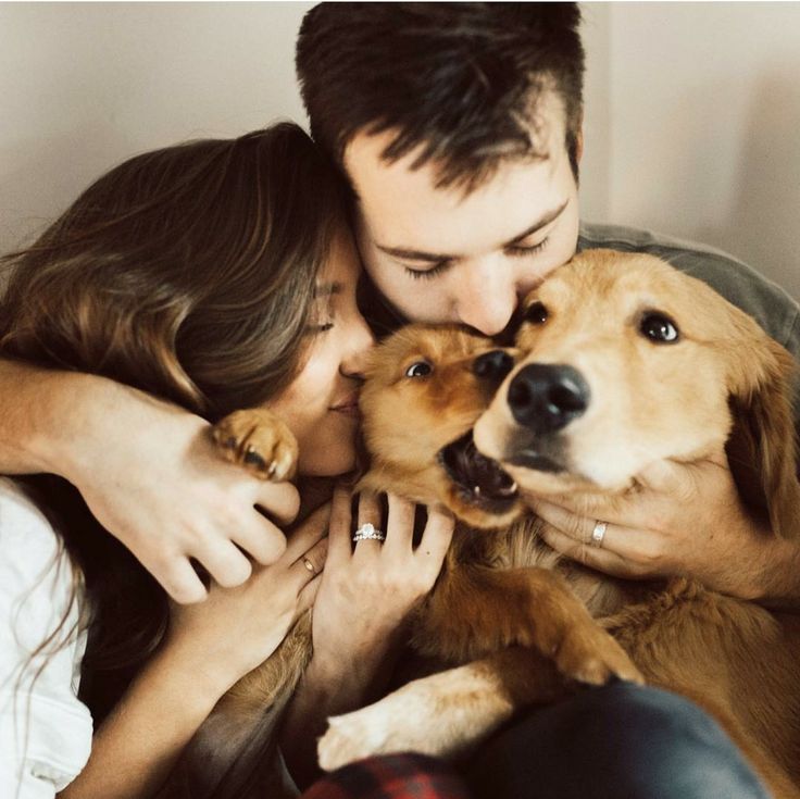 a man and woman cuddle with their dog