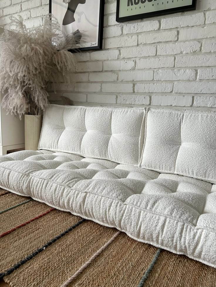 a white couch sitting on top of a rug next to a wall with pictures above it