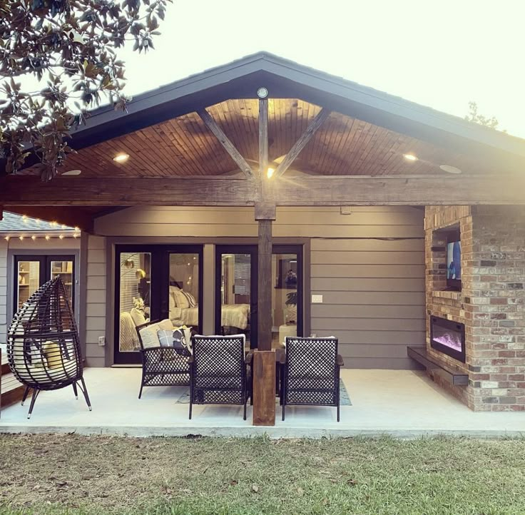 a patio covered in furniture and lights next to a brick building with an open porch