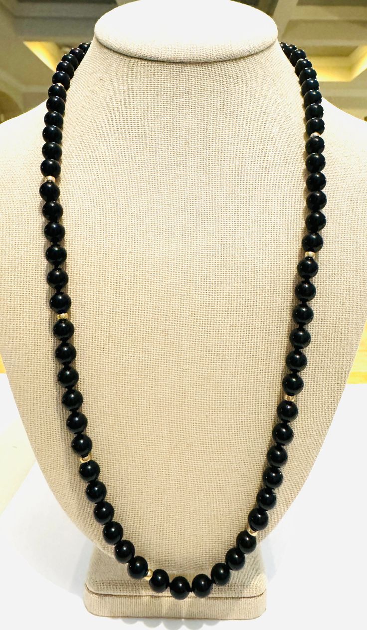 Enchanting vintage 1970s beaded necklace! This elegant necklace features 10mm, natural, hand tied, onyx beads, accented by eight 7.7mm, solid 14k yellow gold beads. The necklace is substantial, weighing 78 grams! It is 27 inches long. This gorgeous necklace is in excellent condition! Vintage Black Gemstone Beads Necklace, Classic Onyx Beaded Necklace With Black Beads, Hand-strung Onyx Beaded Necklaces With Round Beads, Hand-strung Onyx Beaded Necklace With Round Beads, Elegant Black Hand-strung Necklace, Elegant Hand-strung Black Necklace, Vintage Black Beaded Necklace With Gemstone Beads, Elegant Onyx Hand-strung Necklaces, Formal Onyx Beaded Necklace With Round Beads