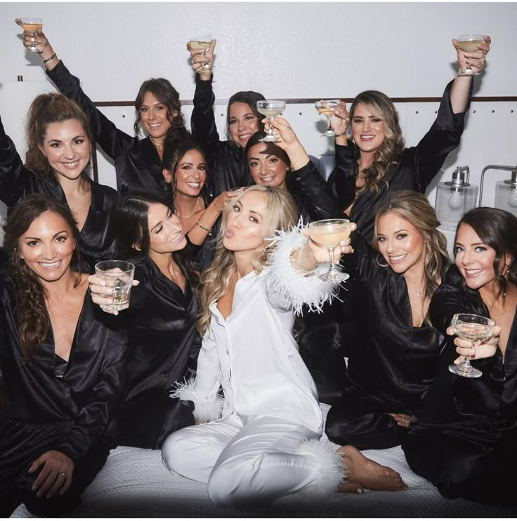 a group of beautiful women sitting next to each other holding wine glasses in their hands