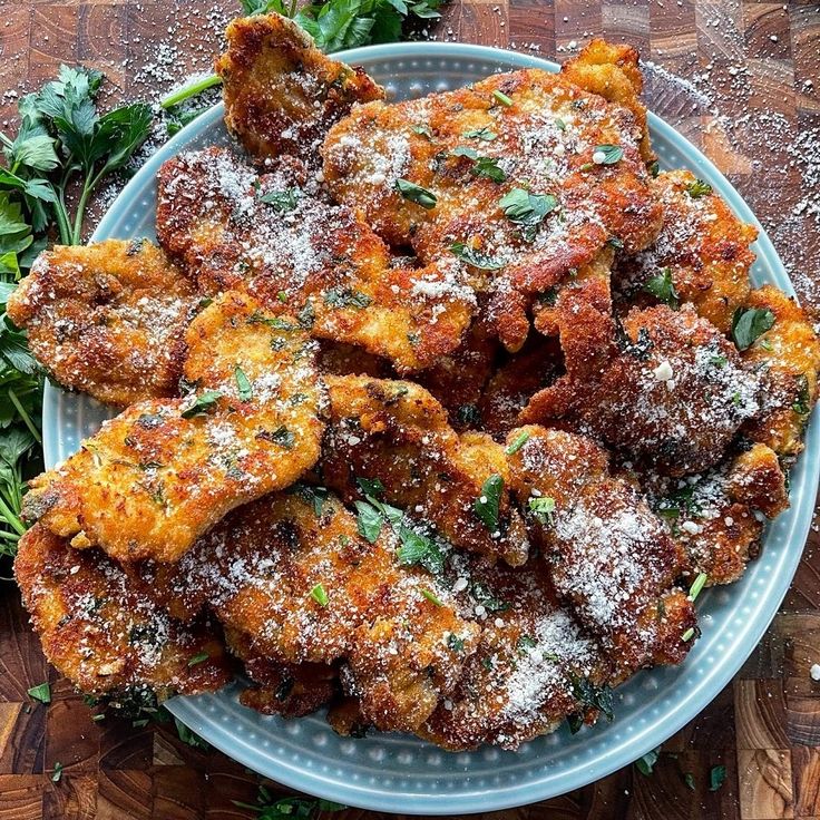 some fried food is on a plate with parmesan cheese and green garnish