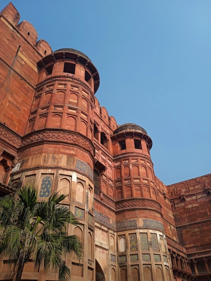 an old brick building with palm trees in the foreground and a blue sky behind it