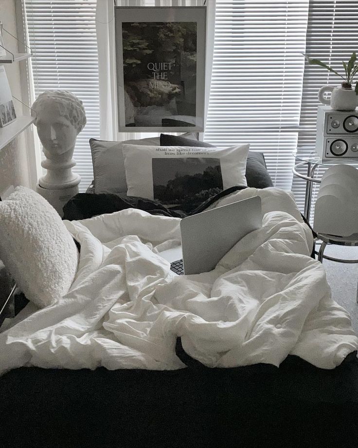 an unmade bed with white sheets and pillows on top of it in front of a window