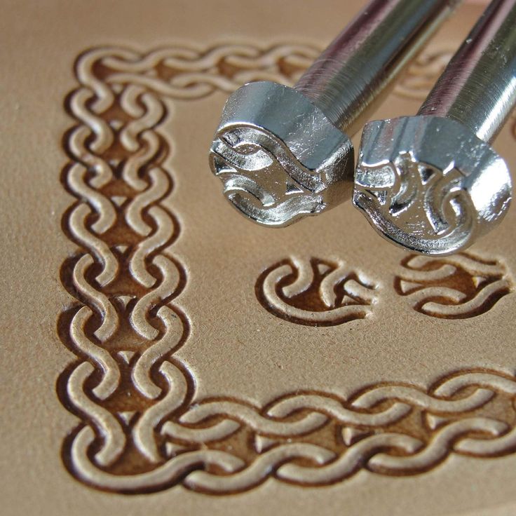 two metal rods sitting on top of a piece of paper with an intricate design in the middle