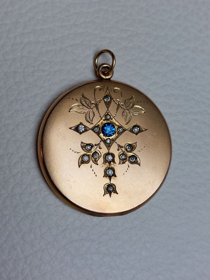 Beautiful Antique Statement Locket with fine engravings, blue, clear rhinestones, and monogram "TS" at the back. Details: The locket was made by the well-known W&H Company from the USA, which stopped operating in 1922. The logo of the company is stamped inside: W&H Co. inside a heart. It is not stamped for gold content but likely made of gold filled which was the typical material used for W&H Co. jewelry. Condition: It is in excellent antique condition, with gentle surface wear and scratches, an Antique Blue Diamond Jewelry, Blue Medallion Jewelry For Anniversary, Antique Blue Locket Jewelry, Victorian Blue Locket Jewelry, Blue Victorian Locket Jewelry, Engraved Round Sapphire Jewelry, Blue Locket Jewelry For Anniversary, Vintage Sapphire Jewelry With Diamond Accents, Formal Blue Locket Jewelry