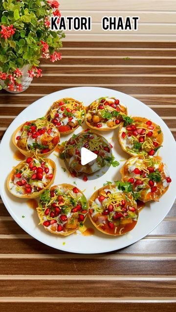 a white plate topped with mini pizzas on top of a wooden table next to a potted plant