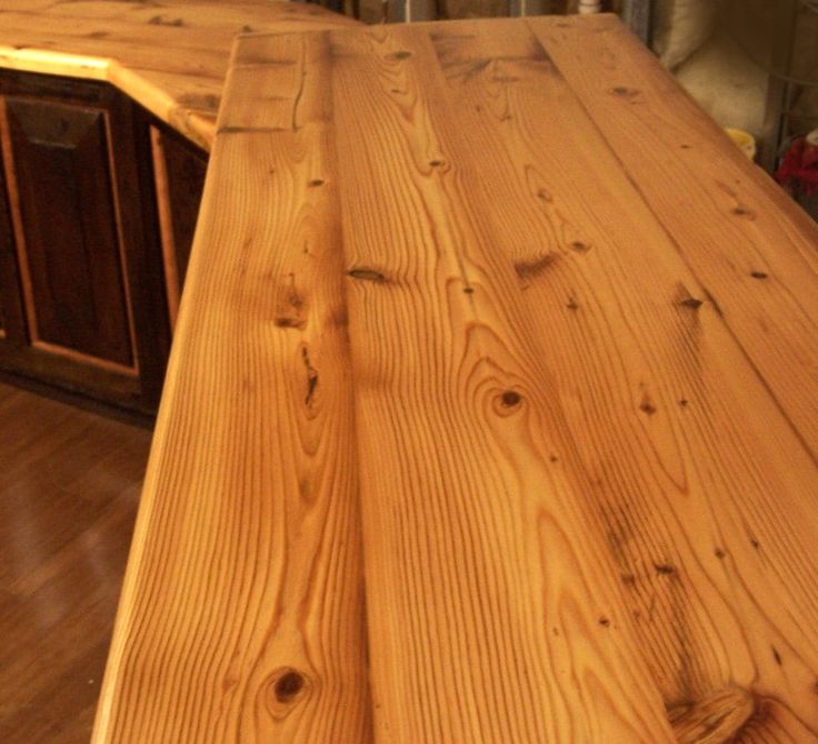 a kitchen counter made out of wood in the middle of a floored room with hardwood floors