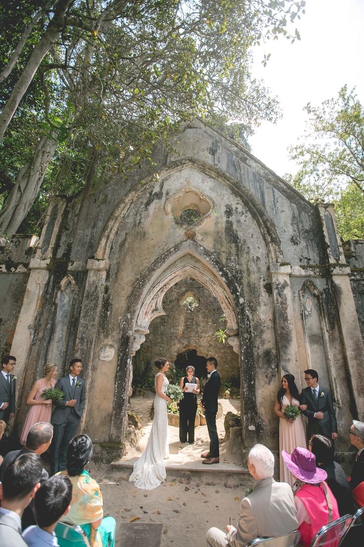 a bride and groom standing in front of an old church with their wedding ceremony guests