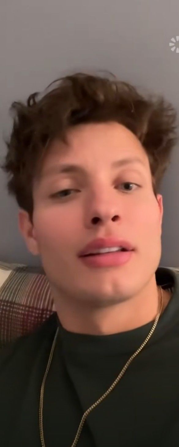 a young man with curly hair wearing a black shirt